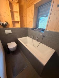 a bathroom with a bath tub and a toilet at Willi's Holidays Home in Saalbach-Hinterglemm