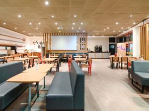 a restaurant with tables and chairs and a screen at Ibis Foz do Iguaçu in Foz do Iguaçu