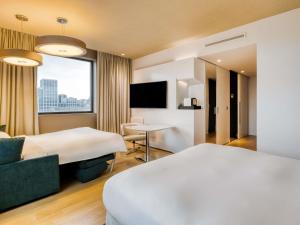 a hotel room with two beds and a table at Pullman Brussels Centre Midi in Brussels +192 photos
