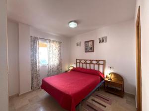 a bedroom with a red bed and a window at Los Enebros in Cartaya +22 photos