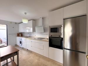 a kitchen with white cabinets and a stainless steel refrigerator at Los Enebros in Cartaya
