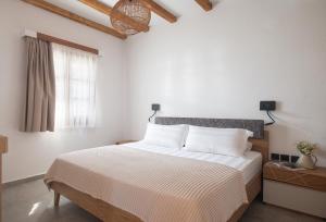 a white bedroom with a large bed with a window at JIRONI VILLA in Nikiti