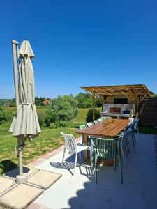 a wooden table with chairs and an umbrella on a patio at Gîte familial 10 pers jardin et piscine in Saint-Amour