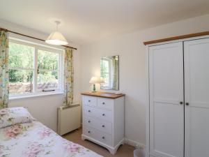 a bedroom with a bed and a dresser and a window at Walk Farm Cottage in Gloucester
