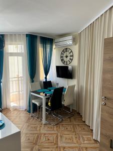 a living room with a table and chairs and a clock at Familienapartment am Strand in Primorsko in Primorsko