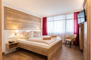 a bedroom with a large bed with a wooden headboard at AktiVital Hotel in Bad Griesbach