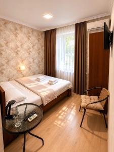 a bedroom with a bed and a table and a chair at Hotel Maria in Tbilisi City