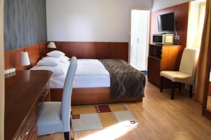 a bedroom with a bed and a desk and a tv at Szieszta Panzió in Sárvár