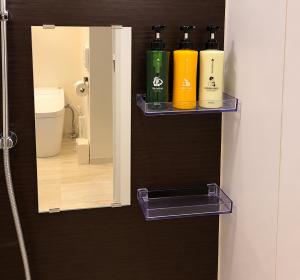 a bathroom with three bottles of shampoo and a mirror at The Aoca Tokyo Kaminoge in Tokyo