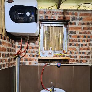 a tv hanging on a brick wall above a toilet at Muong Bi Homestay - Uncle Lon - Luy Ai village in Hòa Bình