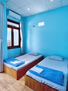 two beds in a room with blue walls at Bọt Biển Homestay Mũi Né in Ấp Khánh Phước (1)