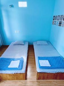 two beds in a room with blue walls at Bọt Biển Homestay Mũi Né in Ấp Khánh Phước (1)