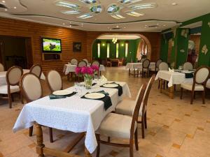 a dining room with tables and chairs with flowers on them at Hotel Orlinoye Gnezdo in Subottsi