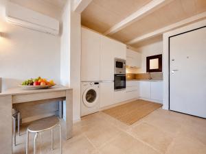 a kitchen with white cabinets and a table and a dishwasher at Renew Terrace RB Two Bedroom 50m from the Beach in Baja Sardinia +12 photos