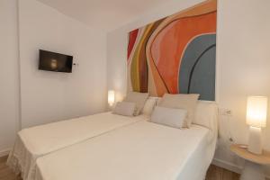 a white bed in a room with a painting on the wall at BiBo Suites Casa Nawal in Granada