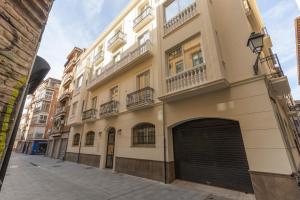 a large white building with a garage on a street at BiBo Suites Casa Nawal in Granada +33 photos