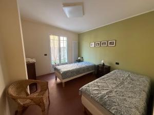 a bedroom with two beds and a chair at Family villa con terrazza e relax in Pietra Ligure