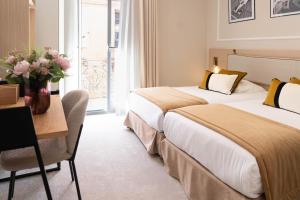 a hotel room with two beds and a table with a desk at Hôtel de France in Monte Carlo