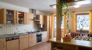 a kitchen with wooden cabinets and a table with a bowl of fruit at Burgerhof in Santa Maddalena in Casies