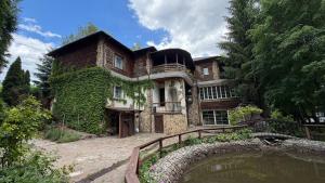 a large house with a pond in front of it at Hotel Orlinoye Gnezdo in Subottsi
