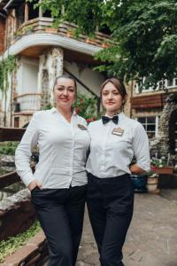 two women wearing white shirts and bow ties standing next to each other at Hotel Orlinoye Gnezdo in Subottsi +111 photos