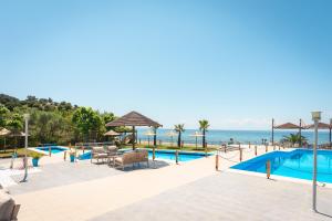 a resort with a swimming pool and the ocean at Kamari Beach Hotel in Potos