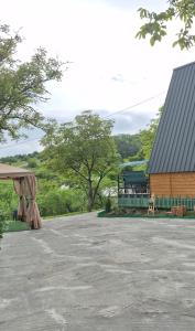 a picnic table and a building with a train in the distance at Pinehouse Urtkhva in Surami in Bugaura