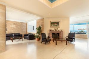 a living room with a fireplace and a couch and chairs at Kamari Beach Hotel in Potos