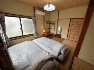 a bedroom with a bed and a window and a door at YADOease in Tsuiki