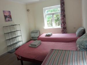 a bedroom with two beds with pink sheets and a window at Special Guest House in Zugdidi