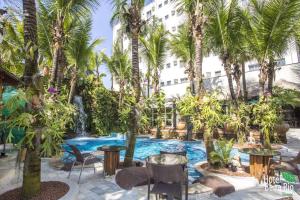 uma piscina de resort com palmeiras e cadeiras e uma fonte em Beira Rio Palace Hotel em Piracicaba