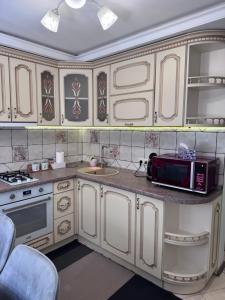 a kitchen with white cabinets and a microwave at Liders17 in Odesa