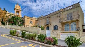 a large building with a clock tower on a street at Stunning villa w Private pool TT table Sleeps 14 in St. Julianʼs