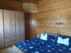 a bedroom with a blue bed with wooden walls at Mangó Vendégház in Balatonszárszó