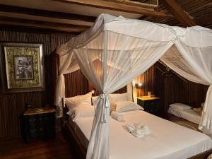 a bedroom with a canopy bed with white curtains at Madabay's Lodge Nosy Be in Antafondro