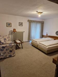 a bedroom with a bed and a couch at Hotel Garni Tonihof in Eschenlohe