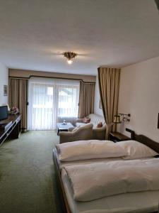 a hotel room with two beds and a couch at Hotel Garni Tonihof in Eschenlohe