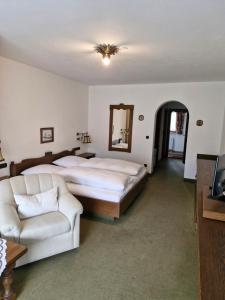 a bedroom with two beds and a couch and a mirror at Hotel Garni Tonihof in Eschenlohe
