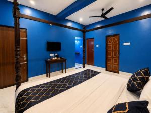 a blue room with a bed and a ceiling fan at Arka by Utkalio in Puri