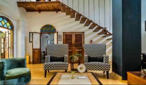 a living room with two chairs and a staircase at Birdsong,Goa in Tivim
