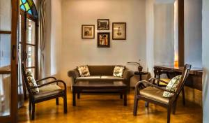 a living room with chairs and a couch and a table at Birdsong,Goa in Tivim