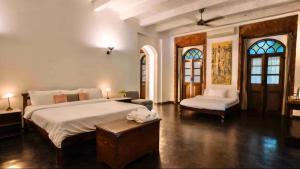 a bedroom with a large bed and a bench and windows at Birdsong,Goa in Tivim
