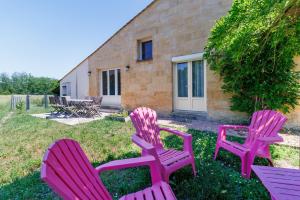 three pink chairs sitting in the grass in front of a building at Chambres D'hôtes Chapetit in Saint-Denis-de-Pile