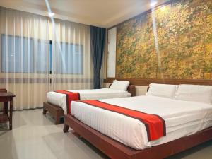 two beds in a hotel room with a painting on the wall at Ease Jomtien by Clubhouse in Jomtien Beach