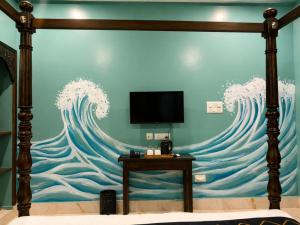 a room with a wall with a painting of waves at Arka by Utkalio in Puri +29 photos