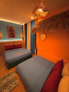 a bedroom with two beds and a thatch roof at Casa Paco Siargao in Catagnan