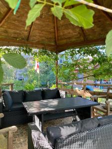 a patio with a table and couches under a roof at Wooden Cottage in Makhinjauri