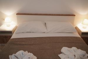 a bedroom with a bed with two lamps on two tables at GARDEN in Nerezine +18 photos