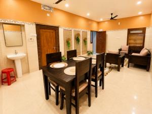 a dining room with a table and chairs and a bathroom at Arka by Utkalio in Puri