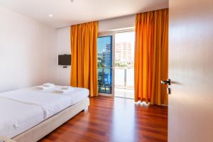 a bedroom with orange curtains and a bed and a window at 3B Suites Boutique Hotel in Sarandë